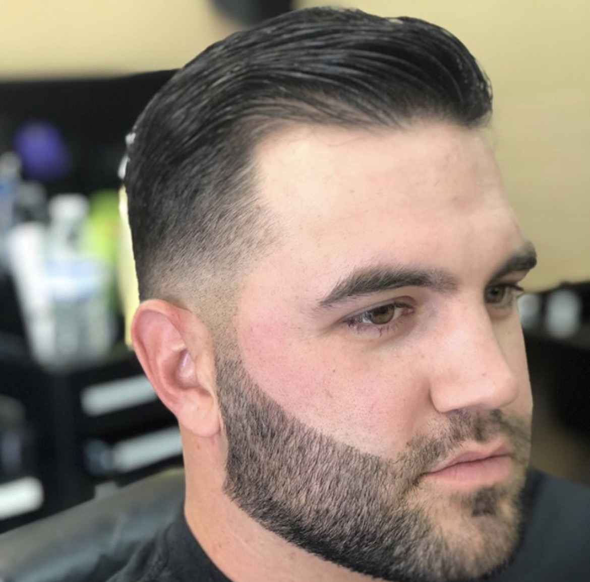 Slick back side part with low fade and beard line